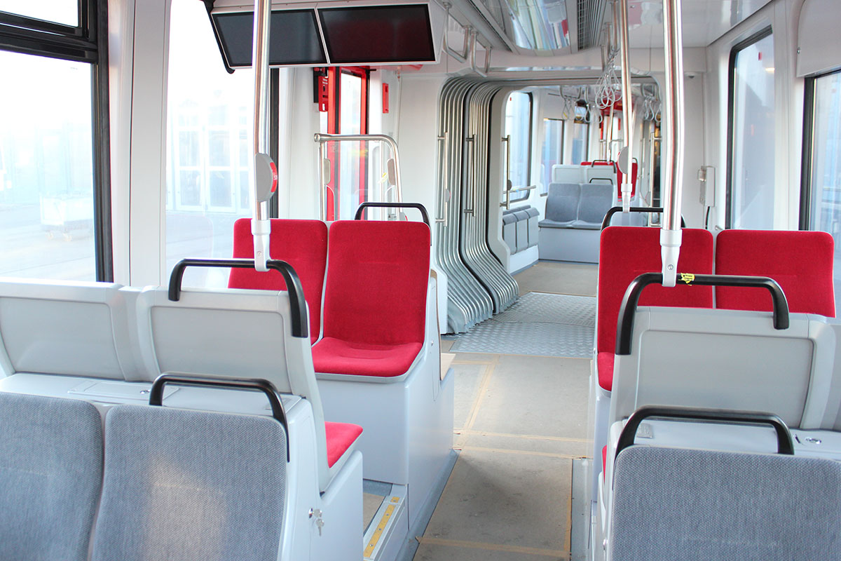 Die neue Straßenbahn "Nordlicht" von innen. Der Boden ist noch mit Schutzpappe abgeklebt. Die Sitze sind mit roten bzw. grauem Stoff überzogen.